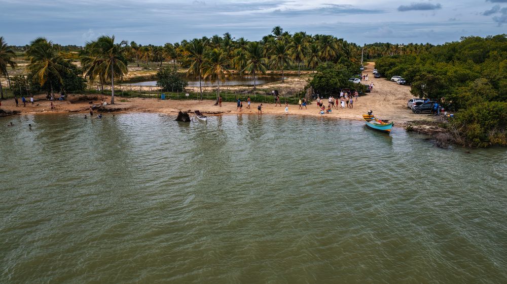 Praia de Boca da Barra com embarcações e coqueiros