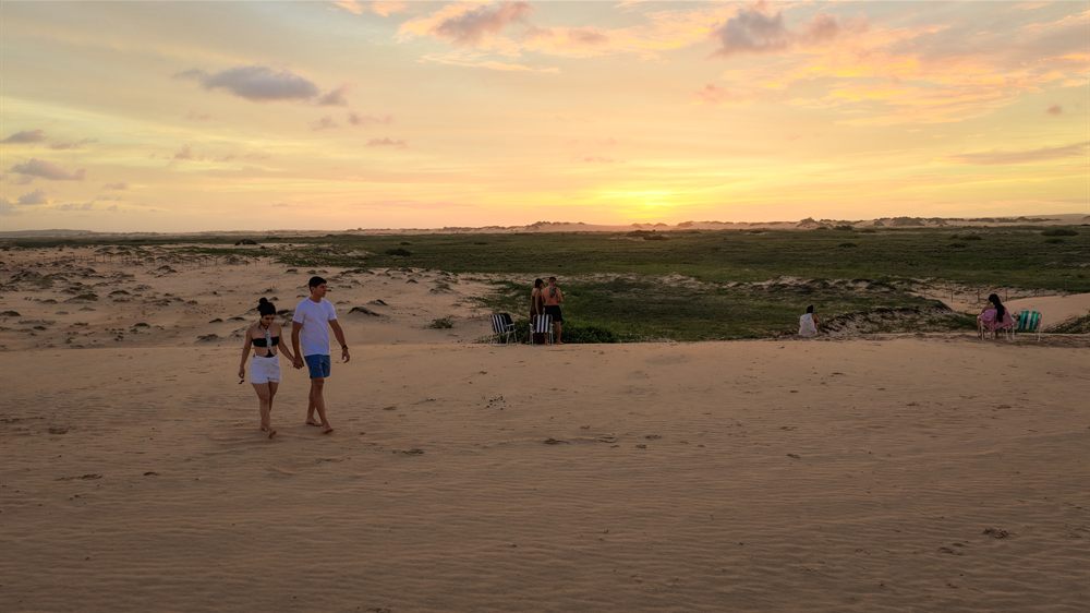 Casal caminhando pelas dunas no fim da tarde